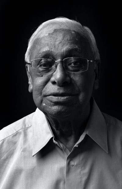 A man dressed in a white button shirt, wearing glasses
